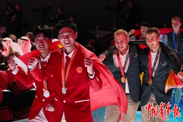 9月27日，上海世博文化中心，第48届世界技能大赛闭幕式现场，在“混凝土建筑”颁奖仪式后，中国代表团选手姚王泽（左二）、张俊豪（左一）身披五星红旗与观众互动。中青报·中青网记者 田嘉硕/摄