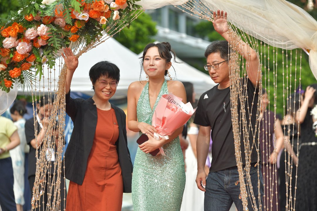 6月10日，北京，中国传媒大学，新闻学院毕业红毯上，家长手扶珠帘，陪同即将毕业的孩子走过毕业拱门。李家瑞/摄