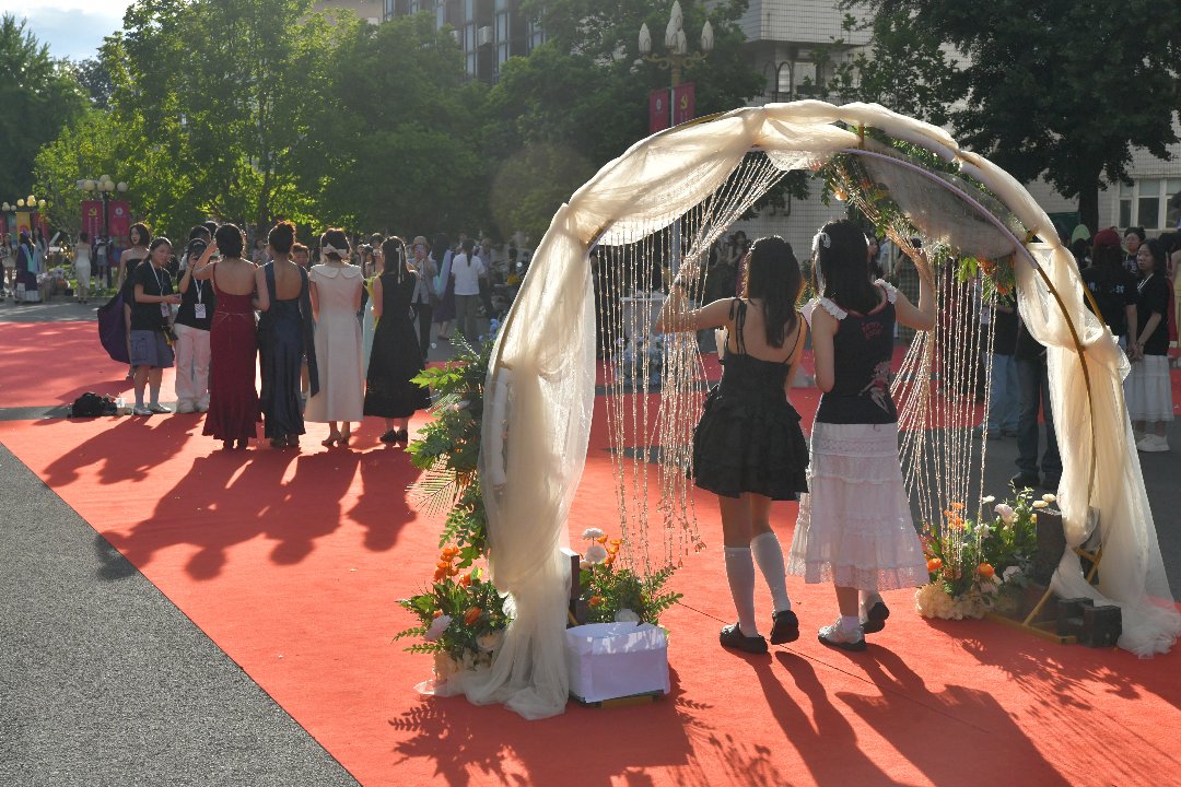 6月10日，北京，中国传媒大学，新闻学院毕业红毯上，两位毕业生共同走过毕业拱门，准备与前方的同学合影留念。李家瑞/摄