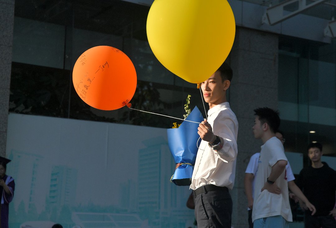 6月10日，北京，中国传媒大学，一位毕业生手持写有朋友祝福的气球。李家瑞/摄