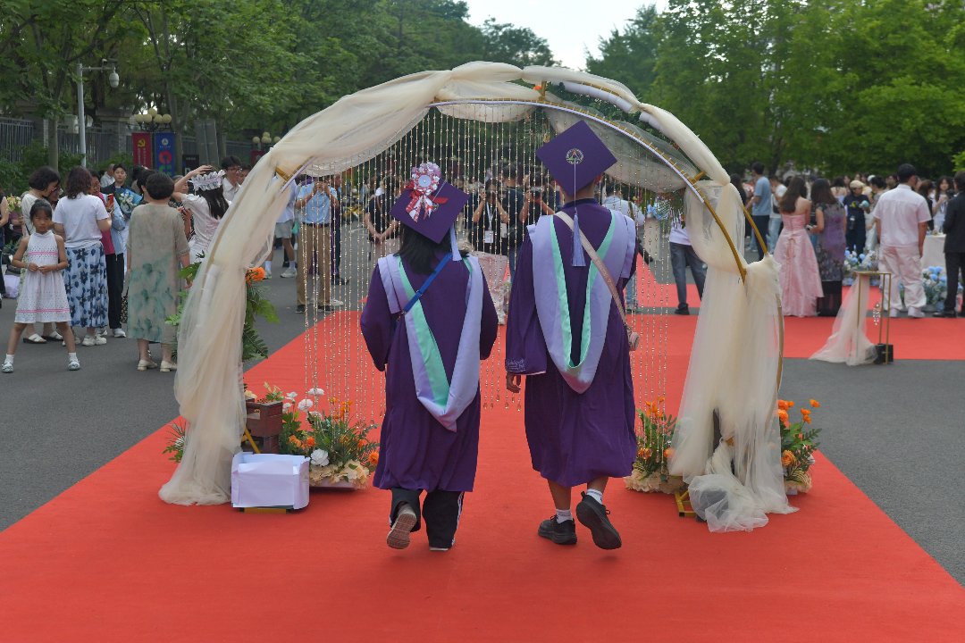 6月10日，北京，中国传媒大学，新闻学院毕业红毯上，两位毕业生共同走向毕业拱门。李家瑞/摄