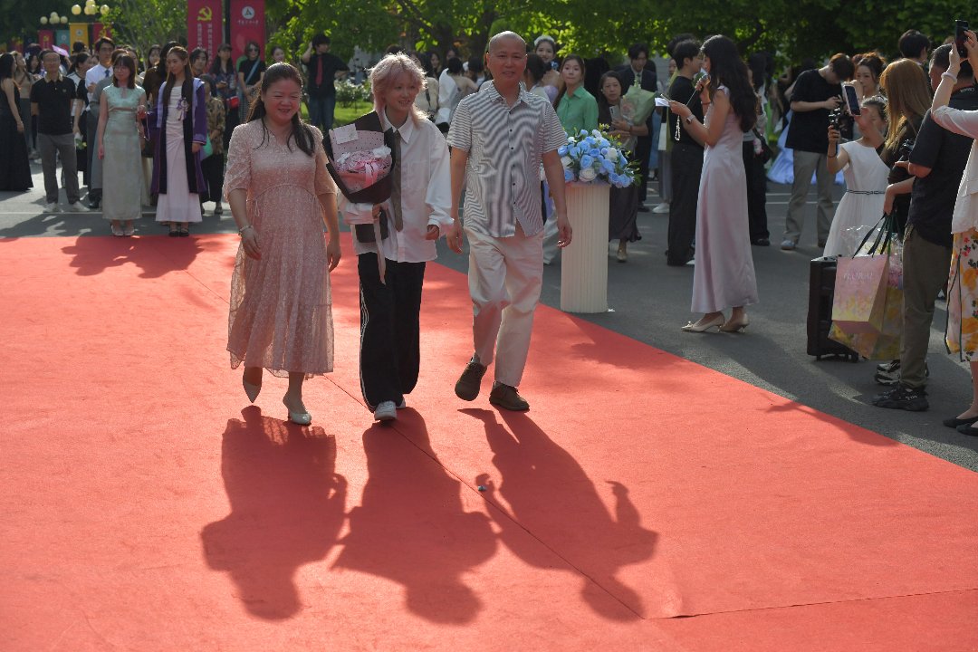 6月10日，北京，中国传媒大学，国际传播学院毕业生在家人陪同下走在毕业红毯上。李家瑞/摄