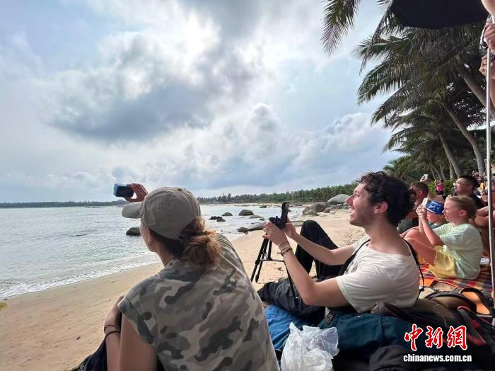 6月11日，法国游客尼科和女友在文昌龙楼镇淇水湾海滩上观看长征五号运载火箭发射。 中新网记者 符宇群 摄