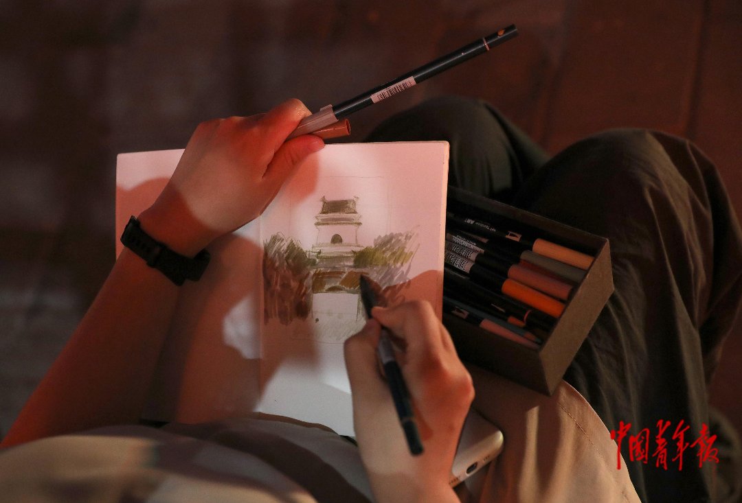 6月20日，北京鼓楼前，一位观众在绘制观影现场的素描画。中青报·中青网记者 陈剑/摄