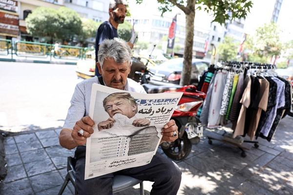 　　6月18日，伊朗德黑兰，一名男子在报刊亭阅读伊朗报纸，报纸上印有美国总统的头像及标题“Gone with the wind”（随风而逝）。视觉中国供图