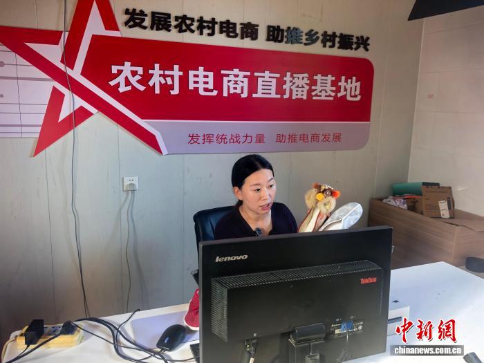 6月11日，返乡青年王亚梅正通过电商直播在网络上销售手工老布鞋。中新网记者 陈林 摄