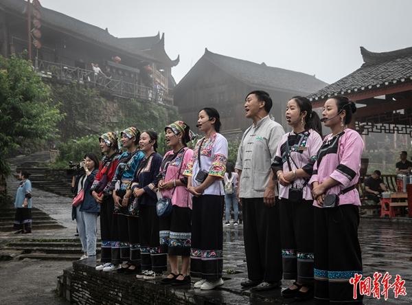 2020年6月11日，湖南湘西土家族苗族自治州花垣县十八洞村，村民唱起山歌送别游客。2013年11月3日，习近平总书记在十八洞村首次提出“精准扶贫”。2016年，全村136户533名贫困人口全部实现脱贫，该村退出贫困村行列。李峥苨/摄