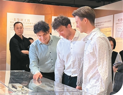齐礼安（右一）和同学在展柜前交流讨论。