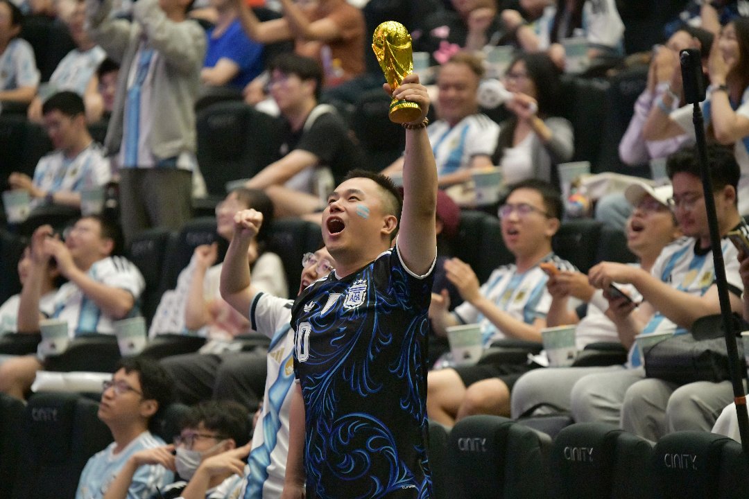 7月12日，北京奥林匹克公园附近一家影院，比赛直播结束后，一名球迷举起大力神杯模型。李家瑞/摄