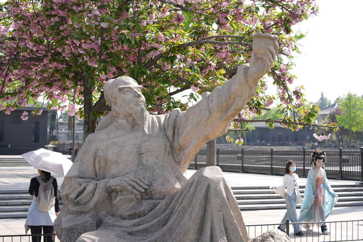 人们在西安市大雁塔北广场上诗人李白造型的雕塑附近游玩（4月9日摄）。新华社记者 邵瑞 摄