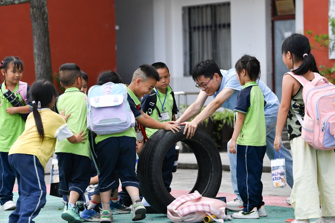 2026年7月10日，贵州省黄平县上塘镇中心小学，一年级学生与徐州医科大学研究生支教团成员王中毅在一起游戏。
