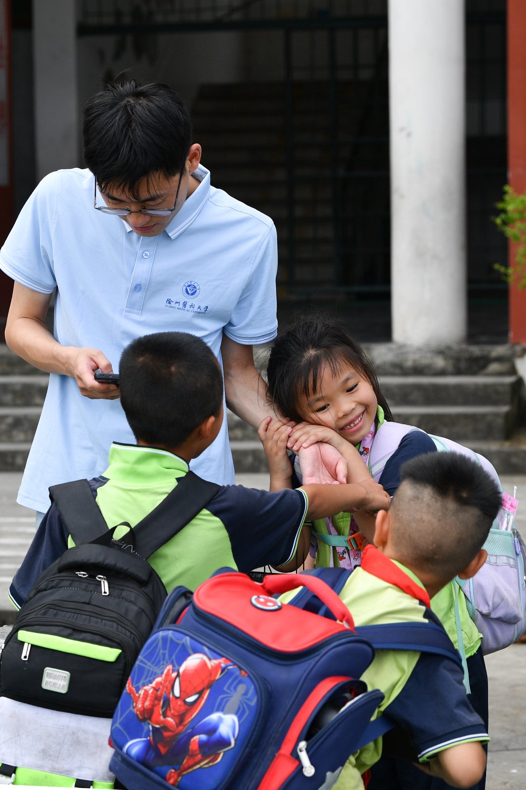 7月10日，贵州省黄平县上塘镇中心小学，一年级学生与徐州医科大学研究生支教团成员王中毅在一起。