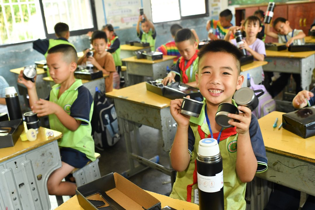 7月10日，贵州省黄平县上塘镇中心小学，一年级学生收到徐州医科大学研究生支教团成员买的25个保温杯。梁文/摄