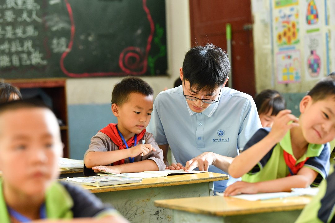 7月10日，贵州省黄平县上塘镇中心小学，徐州医科大学研究生支教团成员王中毅在辅导学生复习。梁文/摄
