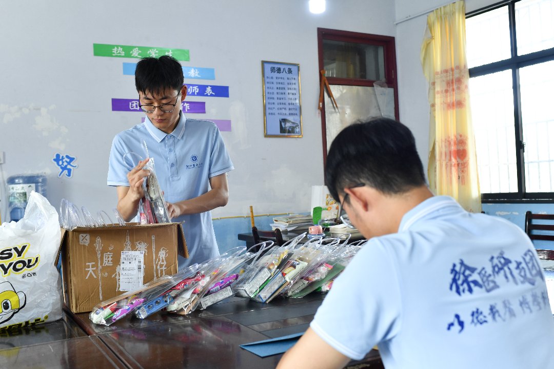 7月10日，贵州省黄平县上塘镇中心小学，徐州医科大学研究生支教团成员袁子坤（右）、王中毅为孩子们准备礼物。梁文/摄