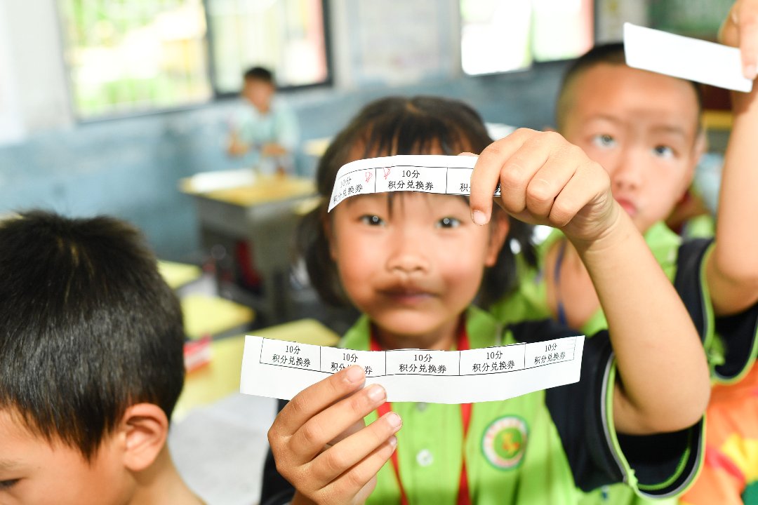 7月10日，贵州省黄平县上塘镇中心小学，一年级学生根据平时表现拿到积分，期末兑现学习用具。梁文/摄