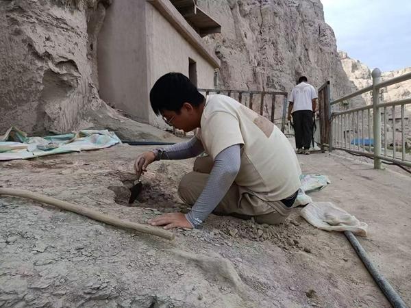 克孜尔石窟第47窟前，周振家在清理窟前建筑遗迹。受访者供图