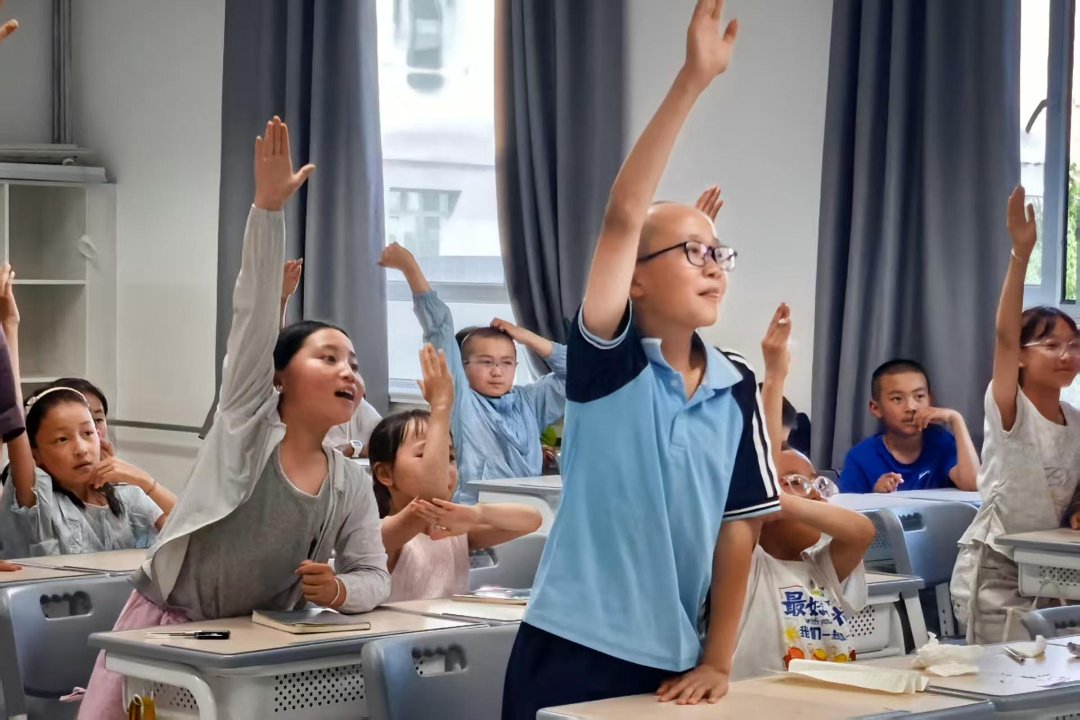 孩子们在天津大学支教大学生的课堂上举手抢答。天津大学供图