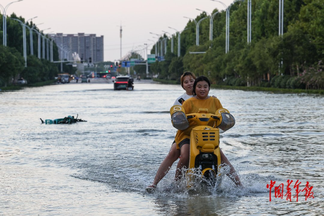 8月16日，河南周口，市民在一处积水较深的街道出行。当天，应急管理部调派的全国13支排涝力量在周口展开作业，协助周口尽快恢复正常出行秩序。目前城区水位持续下降，部分街道仍有积水。中青报·中青网记者 曲俊燕/摄