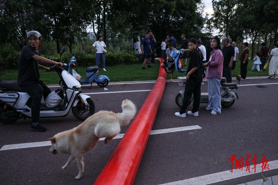 8月16日，河南周口，沙颍河畔，行人将电动车抬过排水管。中青报·中青网记者 曲俊燕/摄