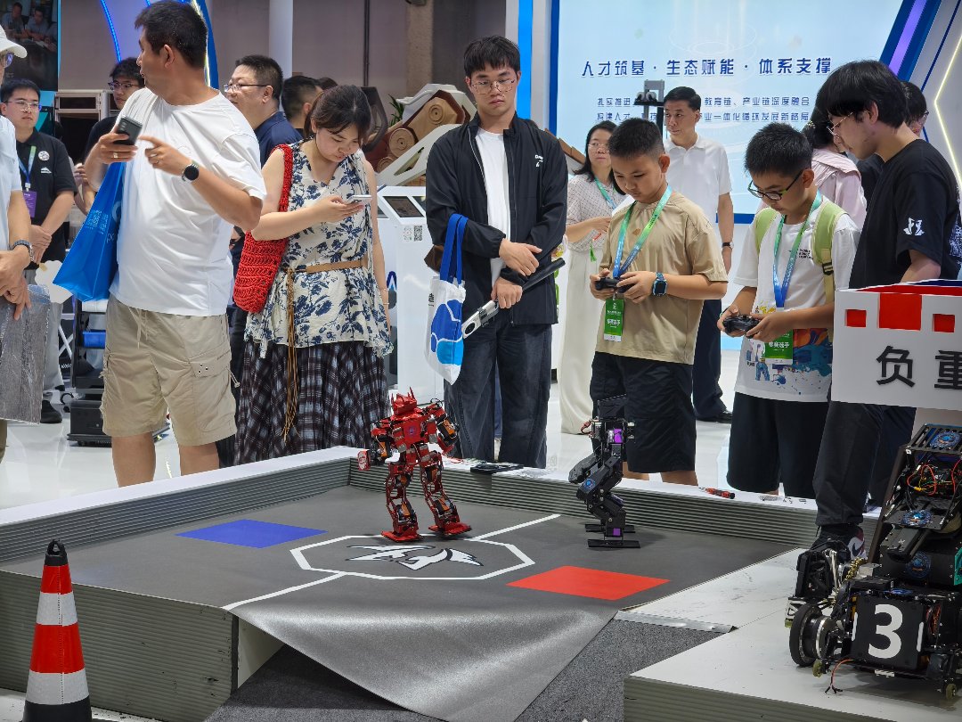 8月19日，北京经济技术开发区，2026世界机器人大会世界机器人博览会展区内，青少年观众正在遥操两款迷你人形机器人。中青报·中青网记者 尹希宁/摄