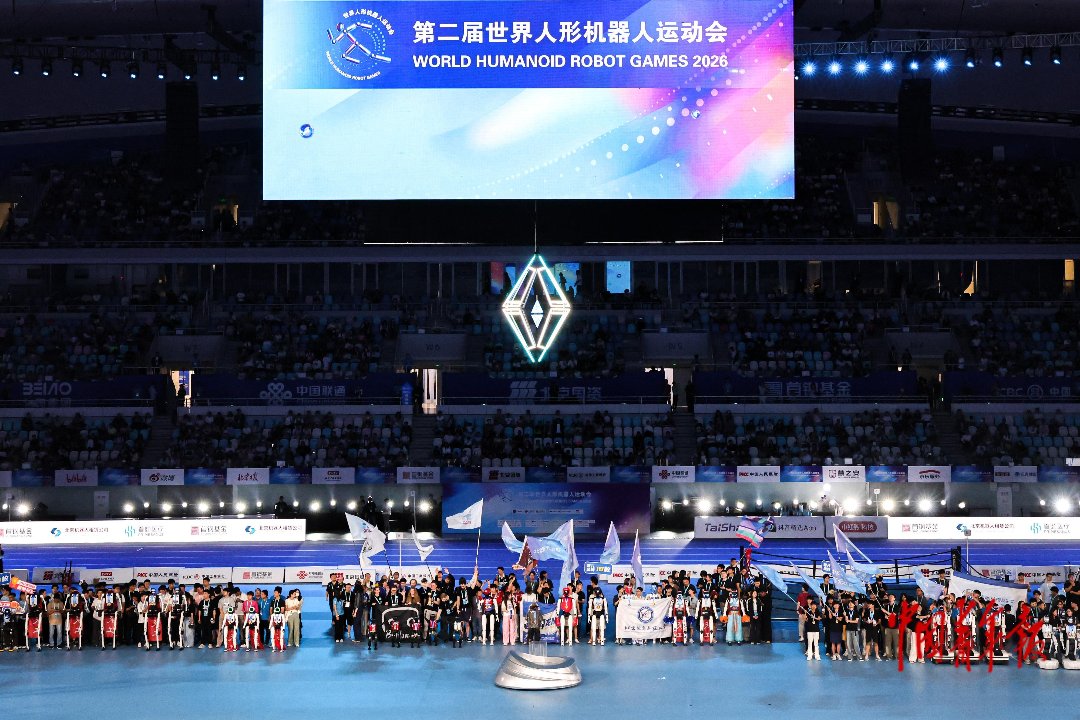 8月26日，北京国家速滑馆，为期5天的第二届世界人形机器人运动会迎来收官之夜，各个队伍的参赛队员和机器人合影。据了解，本届赛事共有来自全球六大洲16个国家的666支队伍参赛，设置51个项目共1301场比赛。竞技赛场上，多项赛会纪录被大幅刷新，其中机器人田径成绩全面突破人类世界纪录。本届赛事为观察全球人形机器人技术演进提供了重要的窗口。中青报·中青网记者 陈思阳/摄
