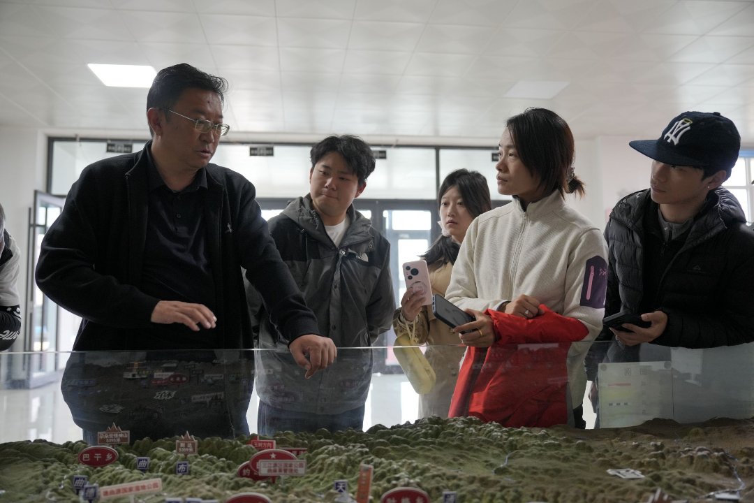 曲麻莱管理处生态环境和自然资源管理局副局长才仁旦周（左）向队员介绍长江源园区保护情况。新疆大学 李林昊/摄