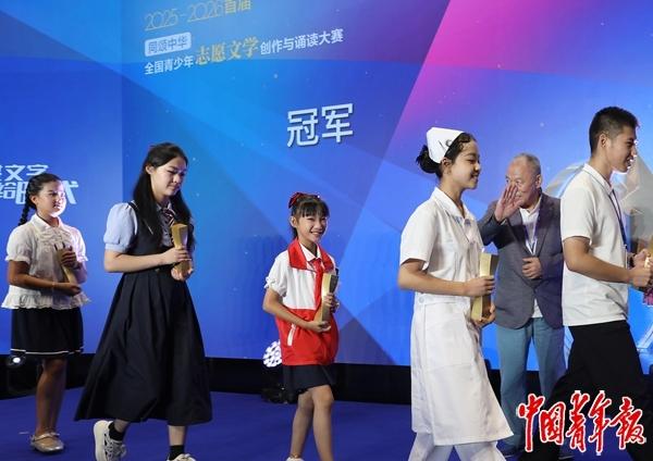 　　8月23日，北京，首届“同颂中华·全国青少年志愿文学创作与诵读大赛”总决赛暨颁奖展演在北京青创IP工厂落下帷幕。颁奖仪式结束后，获得冠军的小选手手捧金灿灿的奖杯喜笑颜开，颁奖嘉宾、著名作家梁晓声（右二）向小选手们挥手致意。中青报·中青网记者 陈剑/摄
