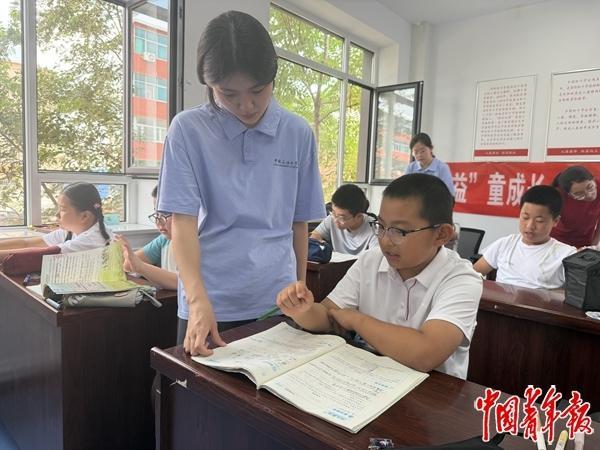 7月28日，在内蒙古通辽市甘旗卡镇团结社区，中国石油大学支教团成员在辅导暑托班孩子写作业。中青报·中青网记者 石佳/摄