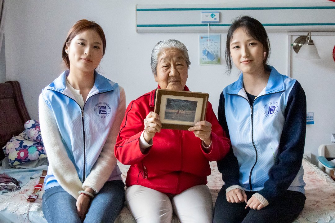志愿者上门为老人送上修复装裱完成的照片。受访者供图
