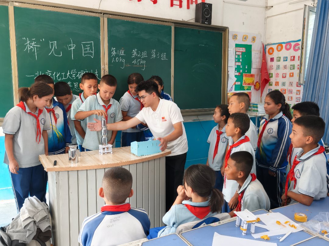 北京化工大学研究生支教团在新疆阿克苏地区新和县第二中学带领同学们进行纸桥承重实验。受访者供图