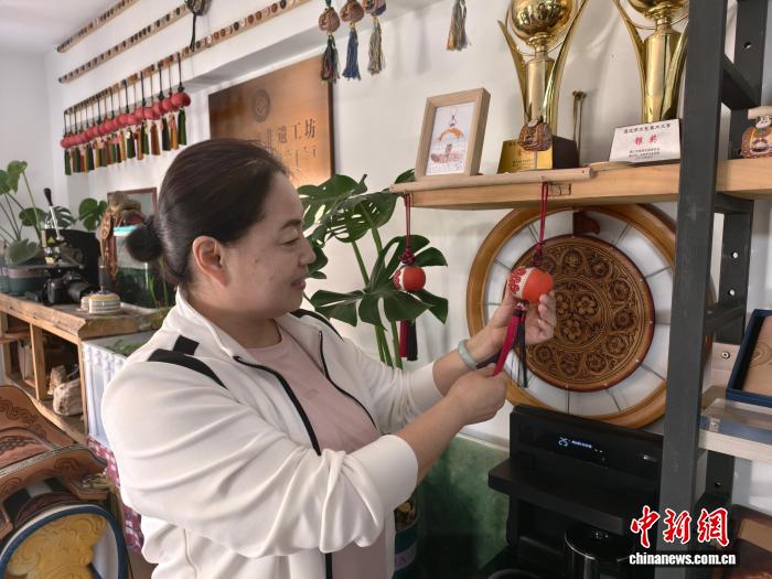 社区居民侯艳霞是非遗皮雕工作室的常客，她给记者展示制作的“小石榴”挂件。中新网记者 勉征 摄