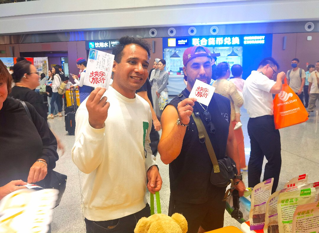 9月24日，北京大兴国际机场，航旅嘉年华现场，两名前往俄罗斯的青年在明信片上盖上了“快乐旅行”印章。李庚伟/摄