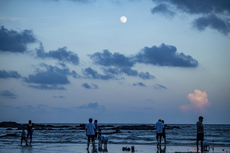 2026年9月25日，海南琼海，游客在沙滩上漫步赏月。