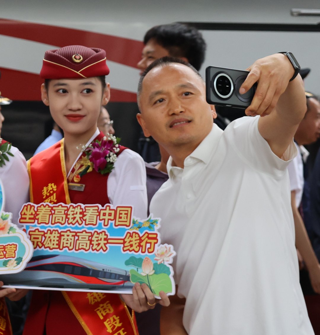等待发车的旅客在站台与列车员合照。梁晓桐/摄