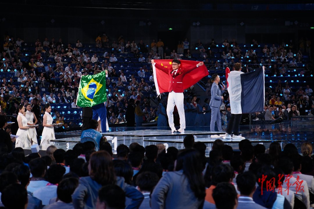 9月27日,上海世博文化中心,第48届世界技能大赛闭幕式现场,在“抹灰与隔墙系统”颁奖仪式上,中国代表团选手薛浩鑫身披五星红旗在领奖台上与观众互动。本届大赛,中国代表团获得41枚金牌、11枚银牌、4枚铜牌,6个优胜奖,第五次位居金牌榜和团体总分世界第一,创造了我国参加世界技能大赛以来的历史最好成绩。中青报·中青网记者 田嘉硕/摄