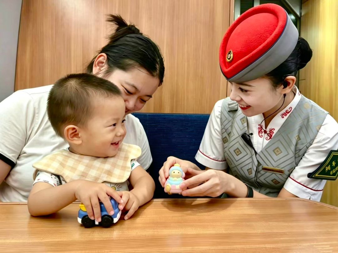 9月29日,青岛开往上海虹桥的G988次列车上,“00后”列车长肖惠匀与一位小旅客交流互动。国庆长假将至,客流高峰叠加,年轻的乘务员们坚守岗位,他们穿梭在车厢与站台,解答问询、疏导秩序,为重点旅客提供帮扶,用细致服务守护旅客平安出行。翟祚珩/摄