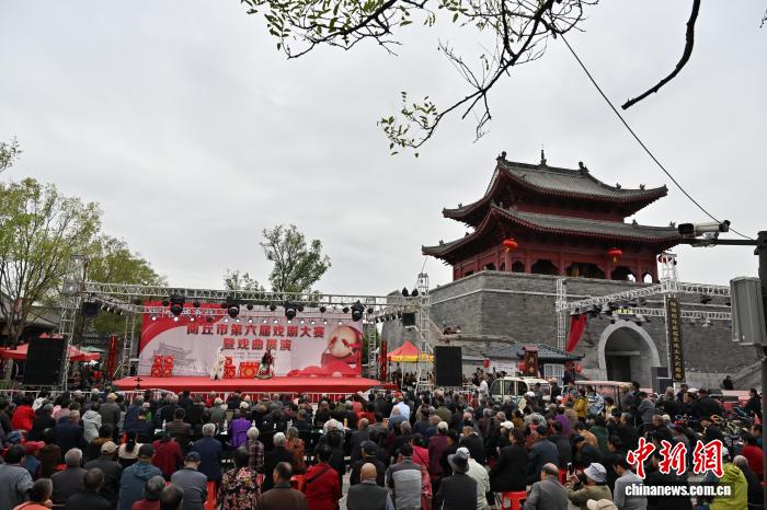 10月1日，国庆假期首日，河南商丘古城人气兴旺，游客漫步古街，沉浸式感受历史文化魅力。图为游客在商丘古城观看戏曲表演。 李恒 摄
