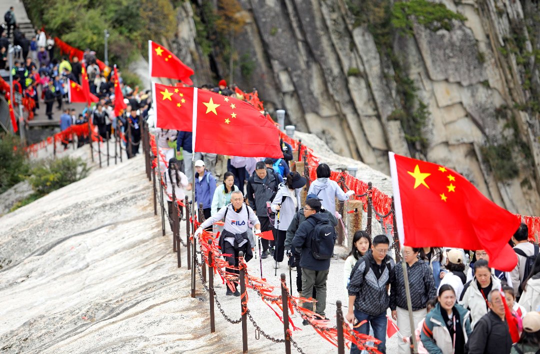 10月1日,国庆节当天,陕西省华阴市,华山西峰,游客登山游览,登山步道两旁五星红旗迎风飘扬。崔正博/摄