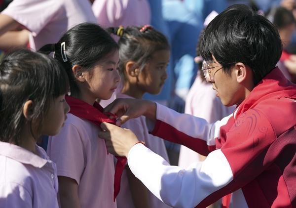 2026年6月1日，杨金桥为北京某小学的小学生佩戴红领巾。视觉中国供图