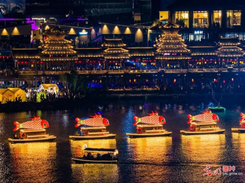 2026年9月25日，广西南宁市民歌湖景区，市民游客乘坐鱼灯游船游览。湖畔灯光璀璨、节目轮番上演，人们在融融夜色中感受浓郁的中秋氛围。(刘峥摄/光明图片)