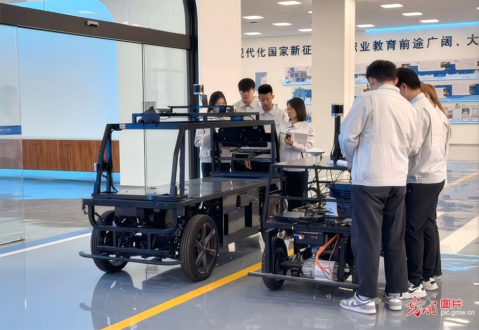 近日，在北京科技职业大学智能网联汽车产业学院，学生们在给无人驾驶车辆进行功能联调。从车载传感器的信号采集到线控底盘的动作响应，学生们分工协作，在真实的工程场景中反复校验数据、排查故障。近年来，北京科技职业大学紧扣汽车产业“电动化、网联化、智能化”转型趋势，将企业真实任务引入课堂，依托“虚拟仿真+真车实训”的进阶模式，让学生在“产业出题、师生解题”的实战中打磨过硬技能。当一技之长与产业前沿同频共振，越来越多的青年学子正凭硬核技能驶入高质量充分就业的“快车道”，在智能网联的新赛道上成就出彩人生。(北京科技职业大学供图/光明图片)