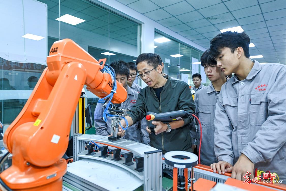 10月19日，江西宜春丰城技师学院机电技术系的老师在向学生讲解工业机器人的操作要领。近年来，江西省丰城市大力发展现代职业教育，以就业市场需求和产业发展实际优化学科专业设置，按照产教融合、校企合作等模式，针对性培养无人机、3D打印、数控加工、工业机器人应用、新能源汽车维修、宠物美容等方面技术人才，不断提升职教学生的就业水平和适岗能力，促进当地职业教育高质量发展。(周亮摄/光明图片)